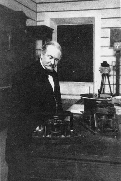 Lo scienziato italiano Antonio Pacinotti (1841-1912) nel suo laboratorio; in primo piano è chiaramente visibile la dinamo da lui ideata; come si può osservare è identica a quella della stampa raffigurata in Fig.10.