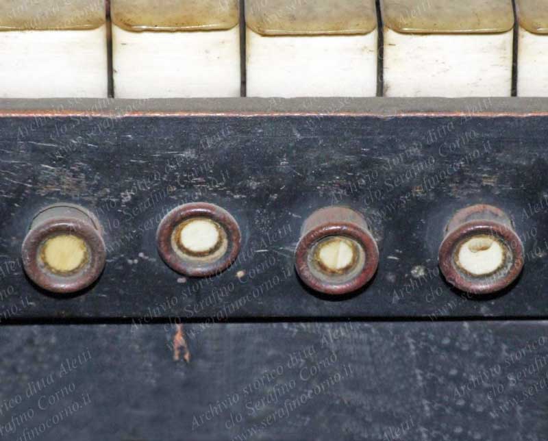 I quattro curiosi e minuscoli pistoncini a comando elettrico che sono posizionati sul frontalino delle tastiere del primo e del secondo manuale; erano stati previsti per l’inserzione di alcuni registri che di seguito elenco, iniziando da sinistra con il N°1. Prima tastiera: N°1-Annullatore / N°2-Principali / N°3-Tromba / N°4- Ripieno. Seconda tastiera: N°1-Annullatore / N°2-Viola da gamba / N°3-Oboe / N°4-Ripieno. Come si può notare non esistono numeri, targhette o riferimenti che indichino la funzione dei pulsanti, mentre per i numerosi pedaletti sottostanti non è così, in quanto sopra ognuno di essi, come ho anticipato, si trova scritto un numero a china. La curiosità di questa consolle consiste nell’avere le funzioni di ogni comando a pistoncino o a pedaletto specificate in due grandi cartelli manoscritti a china (vedi Fig.45), che fanno parte integrante della omonima consolle e che sono stati posizionati rispettivamente a sinistra e a destra, appena sopra i comandi a pomello di ogni registro (vedi Fig.37).